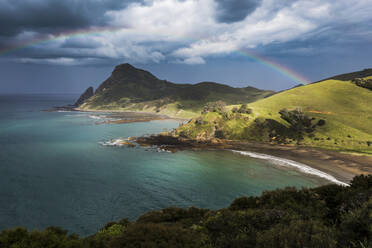 Rainbow arching against storm clouds gathering over coastline of Coromandel Peninsula - WVF01948