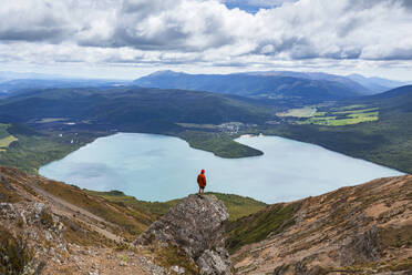 New Zealand, Tasman District, Male hiker standing on top of rock formation overlooking scenic Lake Rotoiti - WVF01986