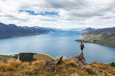New Zealand, Otago, Male hiker admiring view of Lake Hawea from overlooking mountaintop - WVF01995