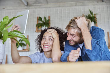 Happy woman taking selfie through digital tablet with boyfriend at home - FMKF07165