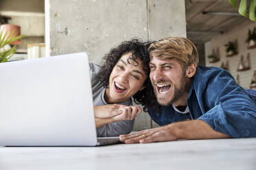 Lachendes Paar bei der gemeinsamen Nutzung eines Laptops - FMKF07177