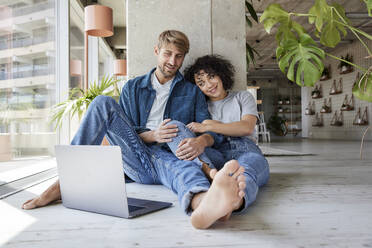 Woman with boyfriend looking at laptop in home apartment - FMKF07178