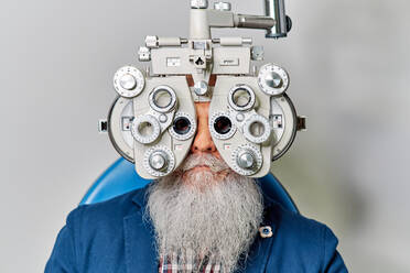 Älterer Mann mit Phoropter bei der Augenuntersuchung - ADSF24287
