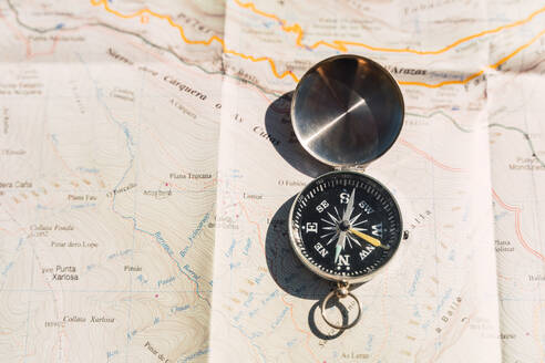 Von oben auf einer Papierkarte platzierter Retro-Kompass, der das Konzept der Navigation und des Reisens zeigt - ADSF24365