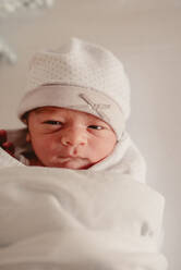 Nahaufnahme niedlichen süßen winzigen neugeborenen Kind in weißen Hut in Decke eingewickelt während der ersten Tage des Lebens - ADSF24486
