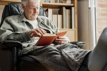 Älterer Mann liest zu Hause ein Buch - AFVF08758