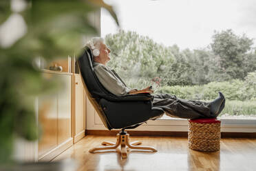 Senior man with eyes closed on chair at home - AFVF08763