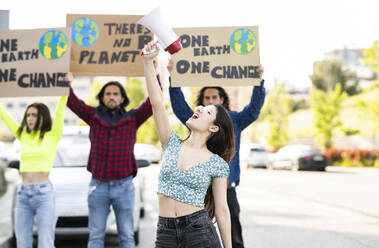 Junge Frau, die mit einem Megaphon gegen den Klimawandel protestiert - JCCMF02430