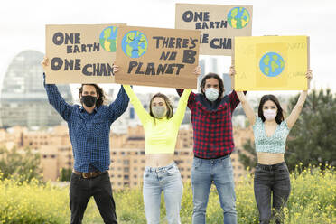 Men with women holding banner amidst plants in city during pandemic - JCCMF02446