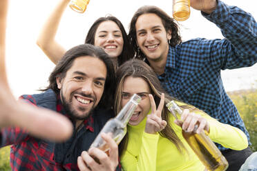 Smiling male and female friends gesturing while enjoying beer - JCCMF02465