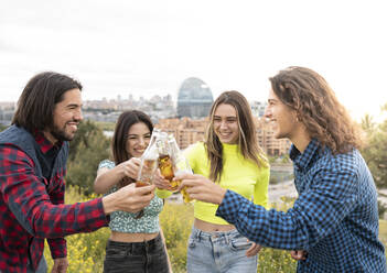 Langhaarige Männer mit Frauen, die auf Bierflaschen anstoßen - JCCMF02469