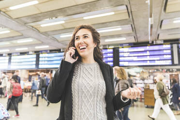 Happy female entrepreneur talking on phone while looking away - WPEF04451