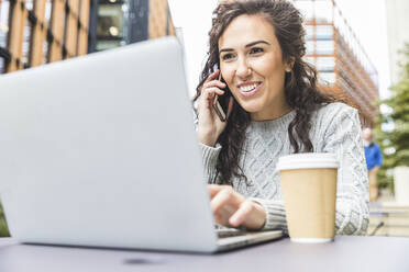 Beautiful female entrepreneur using laptop at cafe in city - WPEF04458