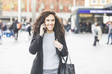 Happy businesswoman using mobile phone in city street - WPEF04466
