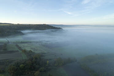 Drohnenansicht der in dichten Nebel gehüllten Landschaft in der Morgendämmerung - RUEF03304