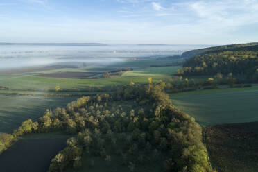 Drohnenansicht der in dichten Nebel gehüllten Landschaft in der Morgendämmerung - RUEF03305