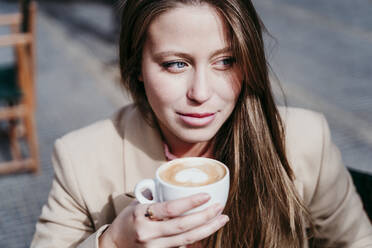 Nachdenkliche junge Frau mit Cappuccinotasse - EBBF03483