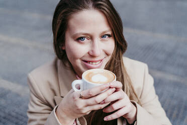 Lächelnde Frau mit Kaffeetasse in einem Straßencafé - EBBF03484