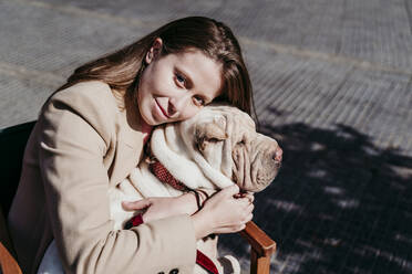 Young beautiful woman embracing pet at sidewalk cafe - EBBF03491