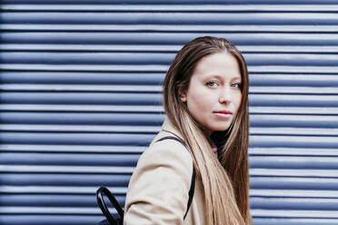 Young woman with long brown hair by shutter - EBBF03513