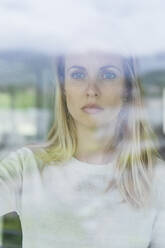 Beautiful businesswoman looking through window at office - MCVF00828