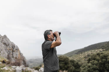 Man looking at view through binoculars on mountain - ASSF00067
