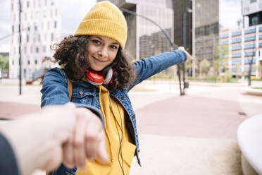 Young woman holding hand of friend in city - JCZF00710