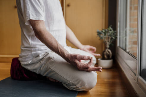 Senior man gesturing OK sign while doing yoga at home - AFVF08773