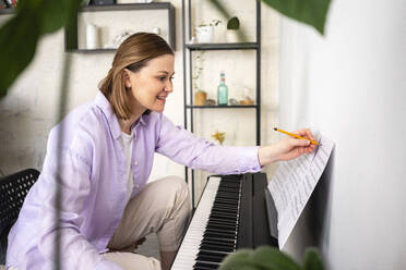 Lächelnde Frau mit Musiknote beim Lernen zu Hause - VPIF03991