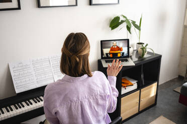 Mid adult woman waving during video call through laptop at home  - VPIF03995