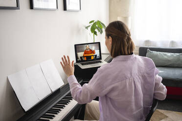 Mittlere erwachsene Frau lernt Klavier mit Online-Tutorial am Laptop zu Hause - VPIF03997