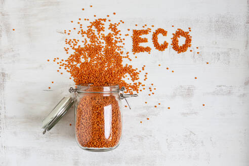 Eco text arranged with orange lentil by open jar on white background - OJF00463
