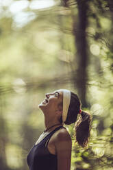 Lächelnde Frau blickt in den Wald - MTBF00993