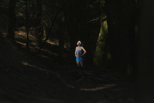 Smiling woman standing in dark forest - MTBF00997