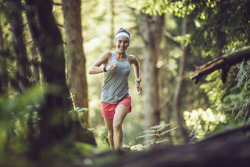Excited female athlete running in forest - MTBF01000
