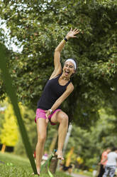 Cheerful young sportswoman slacklining at park - MTBF01012