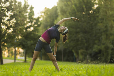 Lächelnde Frau übt Yoga in einem öffentlichen Park - MTBF01018