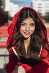 Smiling blue eyed teenage girl wearing red hood jacket on sunny day - JRVF00597