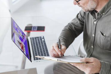Älterer Geschäftsmann arbeitet während einer Videokonferenz über einen Laptop im Büro - MCVF00847