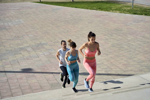 Multi-ethnische männliche und weibliche Freunde joggen auf Stufen im Park - VEGF04466