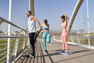 Multi ethnic male and female athlete doing exercise on bridge during sunny day - VEGF04471