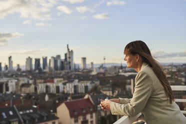 Geschäftsfrau, die auf einem Dach stehend die Aussicht betrachtet - AKLF00162