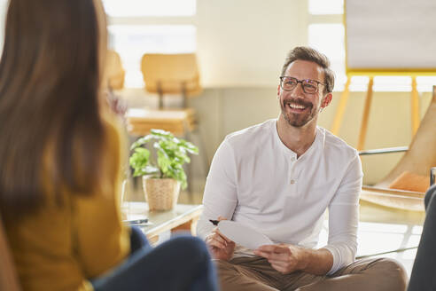 Smiling businessman looking at colleague in creative office - AKLF00205