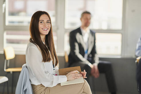 Mid adult female entrepreneur with colleague in conference centre - AKLF00240