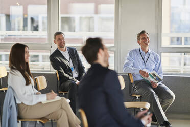 Smiling male entrepreneur with colleagues in education training class - AKLF00242