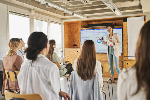 Businesswoman explaining business plan to colleagues in conference centre - AKLF00248