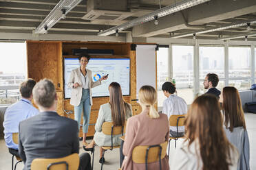 Mid adult businesswoman explaining business strategy to colleagues in training class - AKLF00258