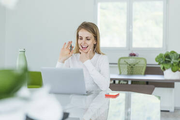 Smiling businesswoman waving during video conference on laptop at office - MCVF00861