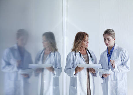 Female doctors discussing over documents in hospital - AJOF01315