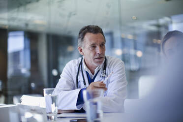 Senior male doctor talking during meeting in hospital - AJOF01328